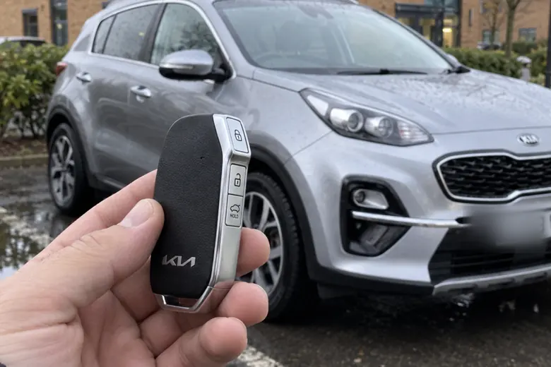 A car key held in front of a Kia Sportage